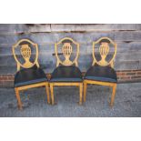 * A set of three satin birch standard dining chairs of Sheraton design with pierced shield-shaped