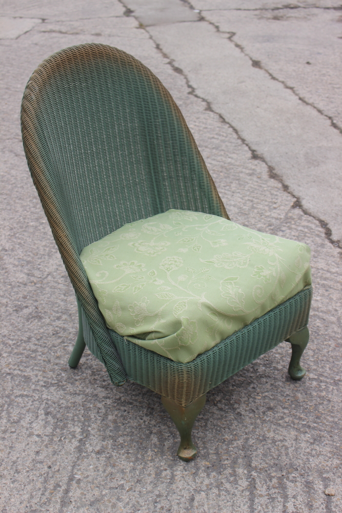 A green and gold painted Lloyd Loom nursing chair with floral upholstered seat, on cabriole supports
