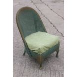 A green and gold painted Lloyd Loom nursing chair with floral upholstered seat, on cabriole supports