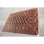 A Bokhara rug with twenty guls on a chocolate ground and multi-bordered in shades of red and blue,