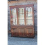 * A mahogany bookcase of Georgian design enclosed three lattice glazed doors over cupboards, 60"