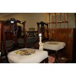 A pair of Edwardian carved mahogany low seat saloon chairs with needlepoint upholstery, on