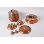 Four copper jelly moulds, a larger similar mould, and a cooking pot and cover