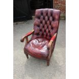 A button back armchair, upholstered in a nailed crimson leather, on turned supports