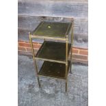 * A brass framed three-tier etagere with green tooled leather inset tops, 12" square x 28" high *