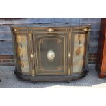 A late Victorian ebonised break bowfront credenza, the centre door inset Sevres enamelled panel with