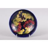 A Walter Moorcroft "Hibiscus" pattern shallow bowl on a blue ground, 7" dia