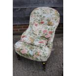 A late 19th century low seat nursing chair, upholstered in a chinoiserie glazed chintz, on turned