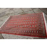 A Bokhara rug of geometric design with sixty central elephant guls on a rust ground and multi-