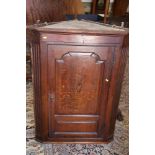 A Georgian oak and shell paterae inlaid corner hanging cupboard, the interior with original paint,