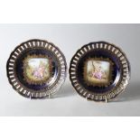 A pair of 20th century Vienna ribbon plates with central painted panels of couples, on a blue