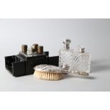 Two cut glass and white metal topped scent bottles, a silver mounted dressing table brush and a