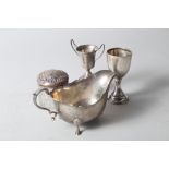 A silver sauce boat, two miniature silver trophies, and a silver and glass dressing jar