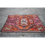 A kelim rug of traditional geometric design with star medallion on an orange ground, 95" x 59"