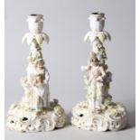A pair of late 19th century Dresden porcelain candlesticks with figures, on scroll bases