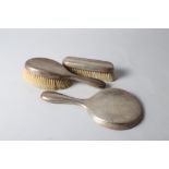 A silver three-piece dressing table brush and mirror set
