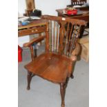 A late 19th century carved oak spindle back elbow chair with dolphin head top rail and panel seat
