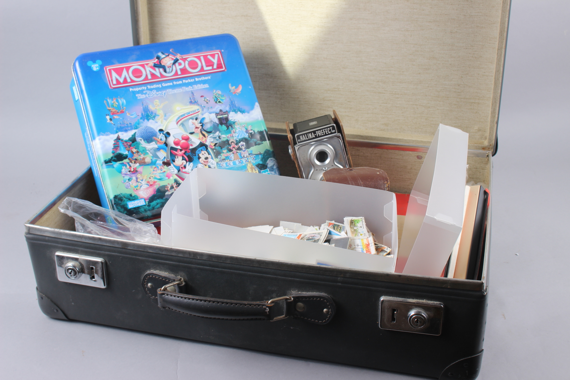 Three Monopoly games, assorted badges, cigarette cards, loose stamps, and a Halina camera, in