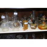 Eight glass oil lamps and a number of shades