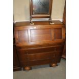 An oak bureau with triple panel front enclosed pigeon holes over three long drawers, on bun feet, 35