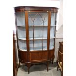 An Edwardian mahogany break bowfront display cabinet enclosed Gothic lattice glazed centre door,