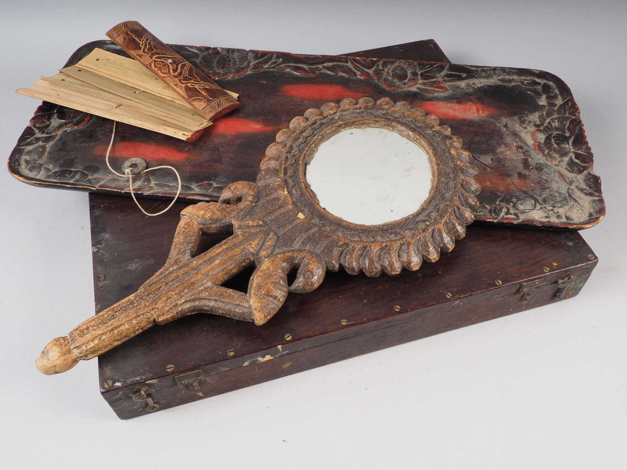 An artist's mahogany travelling paint box, a lacquered carved wooden tray and a hand mirror, in
