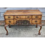 A figured walnut and banded writing desk of Queen Anne design, fitted five drawers, on acanthus