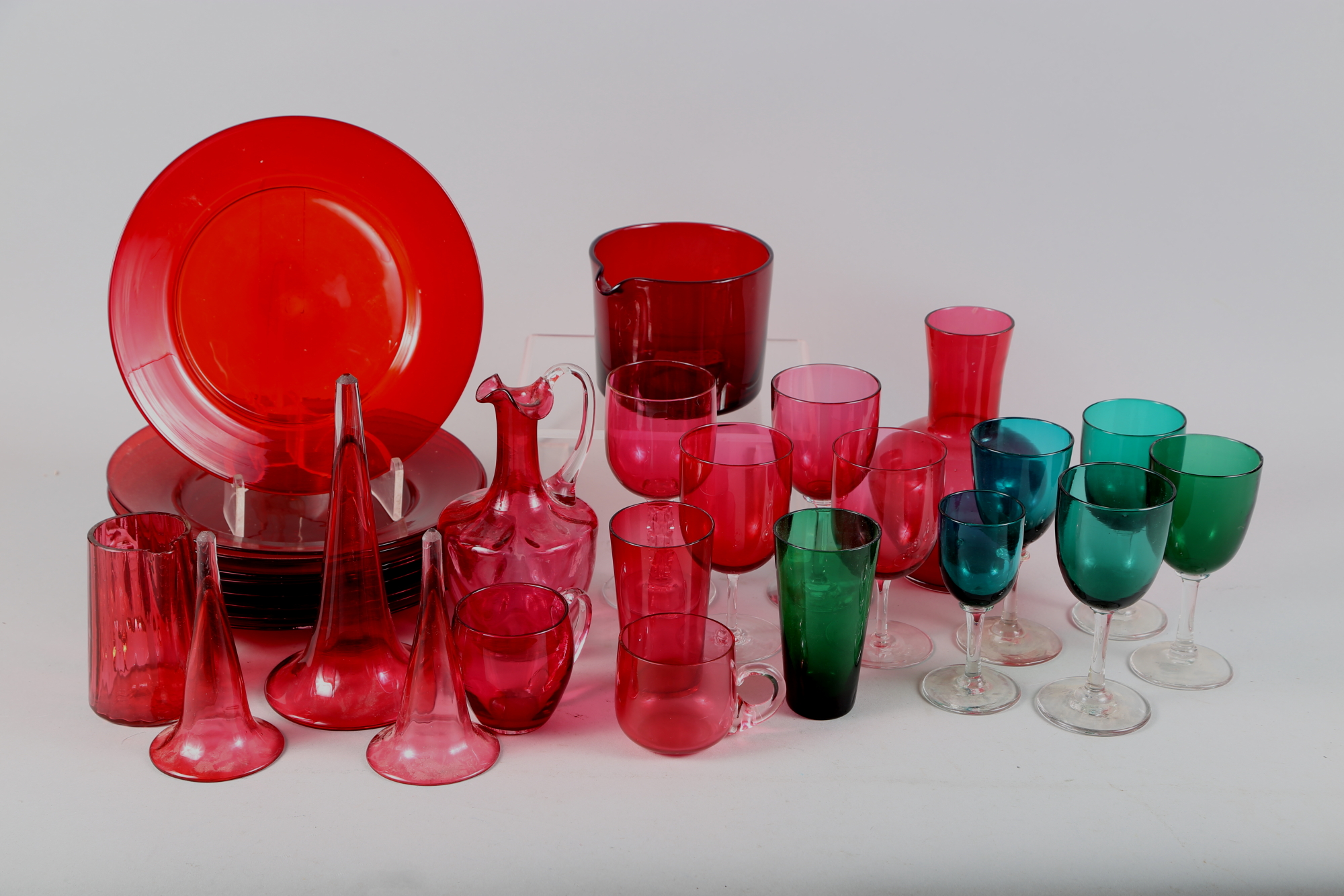 Nine Georgian ruby glass plates, a similar wine glass cooler, three trumpet glasses, five green