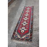 A Kazak style runner with six white crosses on a red ground, 30" x 111" approx