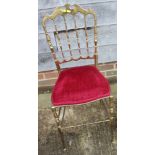 A brass ballroom chair with red velvet seat