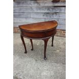 A late Georgian mahogany semicircular fold-over top tea table with deep well, on cabriole supports