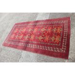 A Caucasian rug with geometric and floral designs and multi-borders on a red ground with shades of