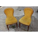 A pair of oak button back side chairs, upholstered in an ochre coloured fabric, on fluted supports