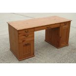 A pine double pedestal desk, fitted drawers and cupboard, on bracket feet, 55" wide x 23" deep x 30"