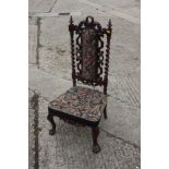 A 19th century carved walnut low seat nursing chair with tapestry panel back and seat, on cabriole