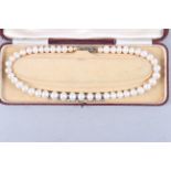A pearl necklace with silver clasp and illusion set brilliant cut diamonds mounted in white