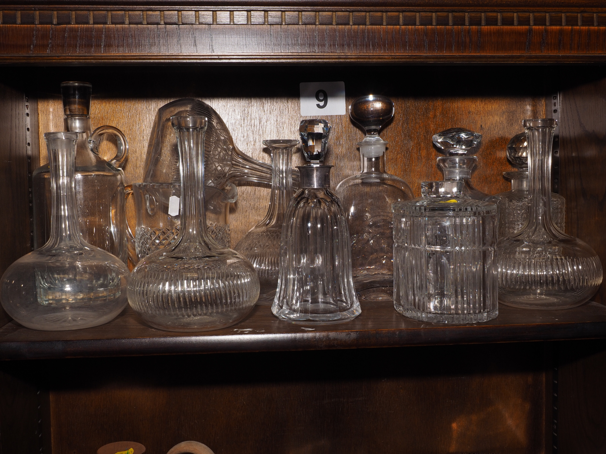 Ten assorted glass decanters, one with silver neck, a glass jug and a biscuit barrel