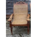 A planter's carved teak and rattan chair with fold-out arms, on turned supports