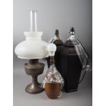 A silvered metal pedestal oil lamp, a pair of bronzed ceramic table lamps and a Portuguese brown