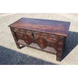 An 18th century dark oak coffer with triple panel front and carved decoration, on stile supports, 25