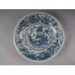 An 18th century Dutch Delft blue and white glazed charger with bird, plant and flower decoration, 13