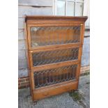 An oak sectional bookcase enclosed leaded doors over one long drawer, on lion paw feet, 34" wide x