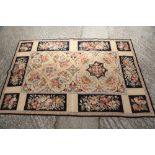 An Aubusson type rug with floral panel designs, 72" x 47" approx, and a circular tapestry cushion