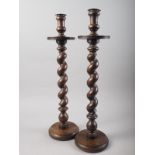 A pair of early 20th century oak barley twist candlesticks, on circular bases