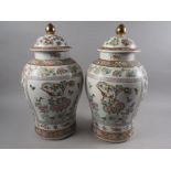A pair of Chinese baluster shaped vases and covers with polychrome flower, fruit, bird insect and