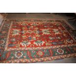 A Kazak style rug with all-over geometric design on a red ground with floral borders, in shades of