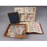 A Coronation stamp album, containing stamps from around the world, two similar stamp albums and a