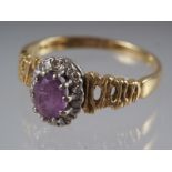 An 18ct gold dress ring set amethyst with collar of diamonds, on textured shoulders, 3.8g gross,
