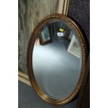 An oval shaped wall mirror with bevelled plate, 26 1/2" x 15 1/2", in gilt frame,