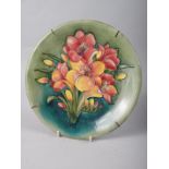 A Moorcroft plate, decorated pink freesias on a green ground, 10 1/4" dia